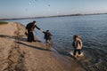 Kids and mom running in water on river bank in autumn. Boy is splashing in river water. Disobedience. Happy family on Royalty Free Stock Photo