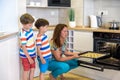 Kids and mother baking. Two children and parent cooking. Little boy and brother boy cook and bake in a white kitchen with modern Royalty Free Stock Photo