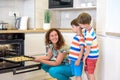 Kids and mother baking. Two children and parent cooking. Little boy and brother boy cook and bake in a white kitchen with modern Royalty Free Stock Photo