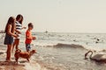 Kids and mother on beach have fun with swan. Royalty Free Stock Photo