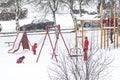 Kids and mother playing in the playground in winter with snow
