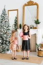 Kids opening Xmas presents. Children under Christmas tree with gift boxes. Decorated living room with traditional fire place Royalty Free Stock Photo