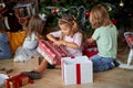 Kids opening Xmas presents. Children under Christmas tree with gift boxes Royalty Free Stock Photo