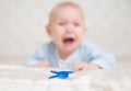 Kids Pacifier in front of crying Baby. Soother and upset Infant Child lying down on Stomach in white Bedroom defocused. Children Royalty Free Stock Photo