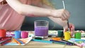 Kids at painting lessons at art club, girl putting paintbrush into water glass