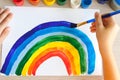 Kids painting watercolor rainbows at table at home. Arts and crafts. Royalty Free Stock Photo