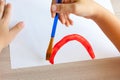 Kids painting watercolor rainbows at table at home. Arts and crafts. Royalty Free Stock Photo