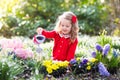 Kids plant and water flowers in spring garden