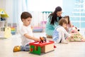 Kids play with educational toys, educator looking after pupils in kindergarten Royalty Free Stock Photo