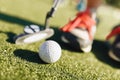 Kids play mini-golf. Close-up image of the player in snickers with mini-golf brassy and golf ball Royalty Free Stock Photo