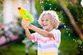 Kids with water gun toy in garden. Outdoor fun Royalty Free Stock Photo