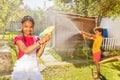 Kids play with water hold gun and garden sprinkler