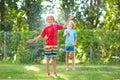 Kids play with water sprinkle hose. Summer garden