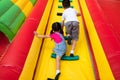 Kids playing the air castle at temple festival. 8 years boy and 4 years girl are climbing slope wall to top of the wall. children Royalty Free Stock Photo