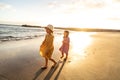 Kids playing on the beach. Little sisters walking at sea shore at sunset. Family summer vacation vibes