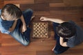 Kids playing chess sitting on wooden floor. Top view. Game, education, lifestyle, leisure concept