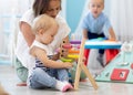 Kids playing on floor with educational toys in kindergarten. Children have fun in nursery or daycare. Babies with