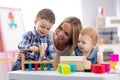 Kids playing with mother at table with educational toys. Toys for preschool and kindergarten. Children in nursery or Royalty Free Stock Photo