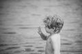 Kids playing - happy game. Cute child waving hand, at seashore. Boy with serious face stand near sea water. Farewell and