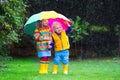 Kids playing in the rain under colorful umbrella