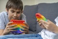 Kids playing with rainbow pop-it fidget toys at home. Push pop it fidgeting game helps relieve stress, anxiety, provide