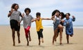 Kids playing running on sand at the beach, A group of children holding hands in a row on the beach in summer, rear view against Royalty Free Stock Photo