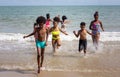 Kids playing running on sand at the beach, A group of children holding hands in a row on the beach in summer, rear view against Royalty Free Stock Photo