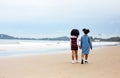 Kids playing running on sand at the beach, A group of children holding hands in a row on the beach in summer, rear view against Royalty Free Stock Photo