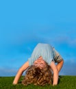 Kids playing upside down on grass outdoors in summer park. Children playing on nature. Copy space on blue sky.