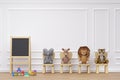 Kids playroom with stuffed toy animals wood stool and writing board.
