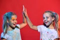 Kids with ponytails make high fives. Schoolgirls have paint spots