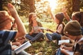 Kids raising hands asking questions during outdoor lesson with teacher in forest on sunny spring day Royalty Free Stock Photo