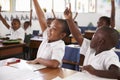 Kids raising hands during elementary school lesson, close up