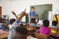 Kids raising hands to teacher in an elementary school class