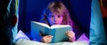 Kids reading a book in the dark home. Child boy reading a book lying on the bed. Dreaming child read bedtime stories Royalty Free Stock Photo
