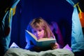 Kids reading a book in the dark home. Child boy reading a book lying on the bed. Kids face with night light. Concept of Royalty Free Stock Photo