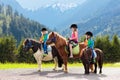 Kids riding pony. Child on horse in Alps mountains Royalty Free Stock Photo