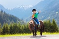 Kids riding pony. Child on horse in Alps mountains Royalty Free Stock Photo