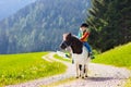 Kids riding pony. Child on horse in Alps mountains