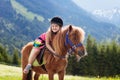 Kids riding pony. Child on horse in Alps mountains