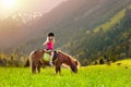 Kids riding pony. Child on horse in Alps mountains