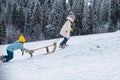 Kids riding sledding slide. Children on snow landscape, winter snowy fun activities. Sled speed riding or childhood Royalty Free Stock Photo