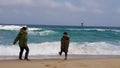 Kids running away from sea waves in winter jackets