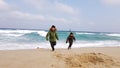 Kids running away from sea waves in winter jackets