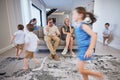 Kids running, mother and father on sofa tired and chaos in living room. Frustrated parents burnout, happy children and Royalty Free Stock Photo