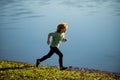 Kids running outdoors. Sporty young child jogging and training outdoor. Child running on summer field near lake, kids Royalty Free Stock Photo