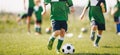 Kids running after soccer ball at natural grass sports field. Group of children training football skills at physical education Royalty Free Stock Photo