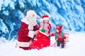 Kids and Santa Claus opening presents in snowy forest Royalty Free Stock Photo