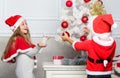 Kids in santa hats decorating christmas tree. Family tradition concept. Children decorating christmas tree together