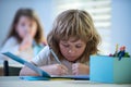 Kids at school. School child writing something in copybook and sitting at table in classroom. Royalty Free Stock Photo